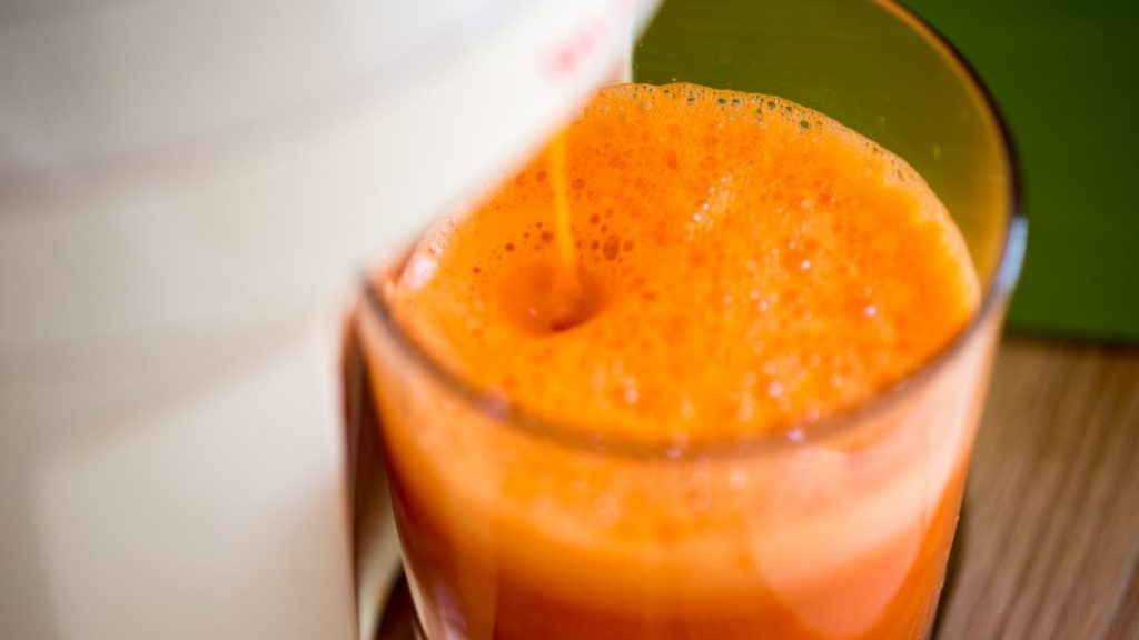 carrot juice running and filling glass